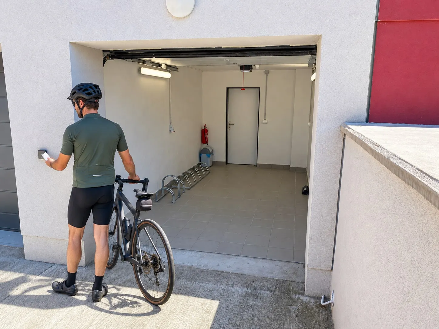 Cyklista otevírá kartou od pokoje hotelovou garáž se stojanem na kola