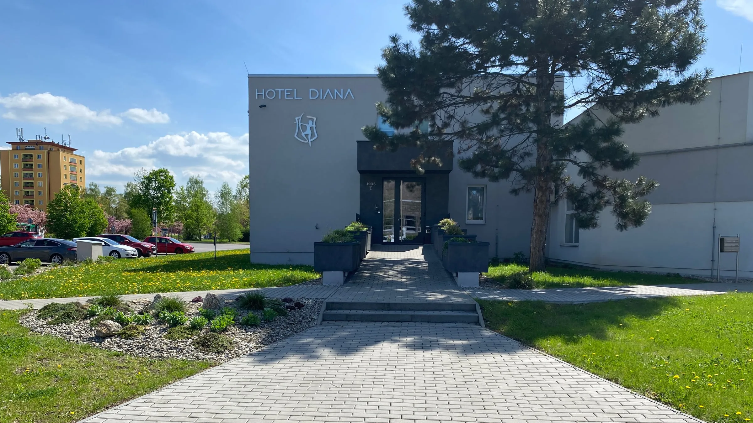 Vchod do Hotelu Diana, vlevo parkoviště s auty